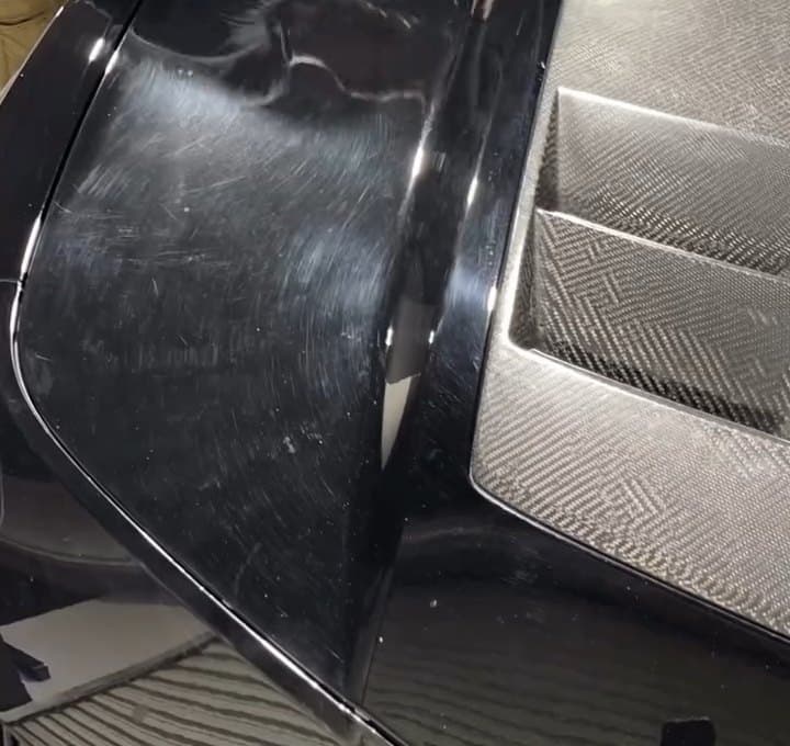 Black panel covered in swirl marks and scratches before paint correction